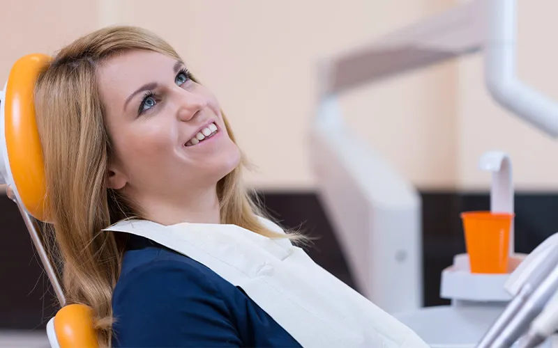 A blonde girl smiles in the dentist's chair