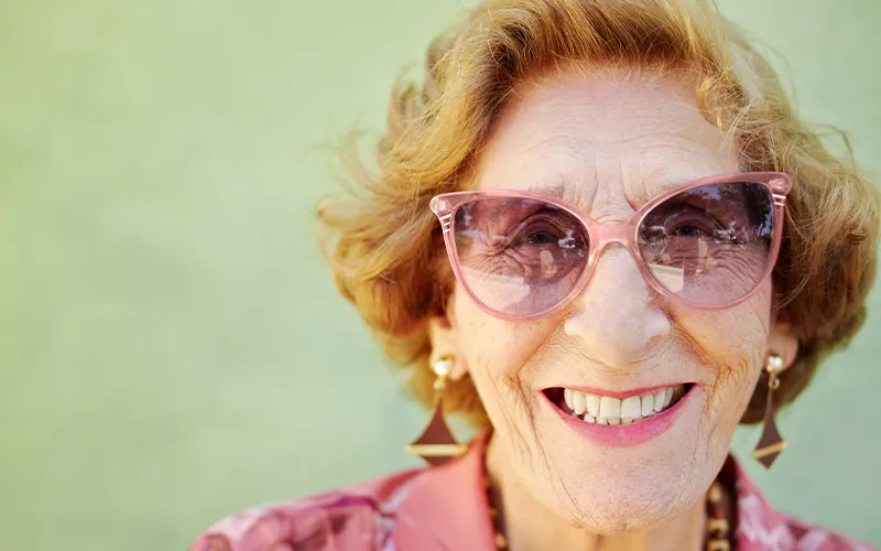 Smiling elderly woman wearing pink glasses
