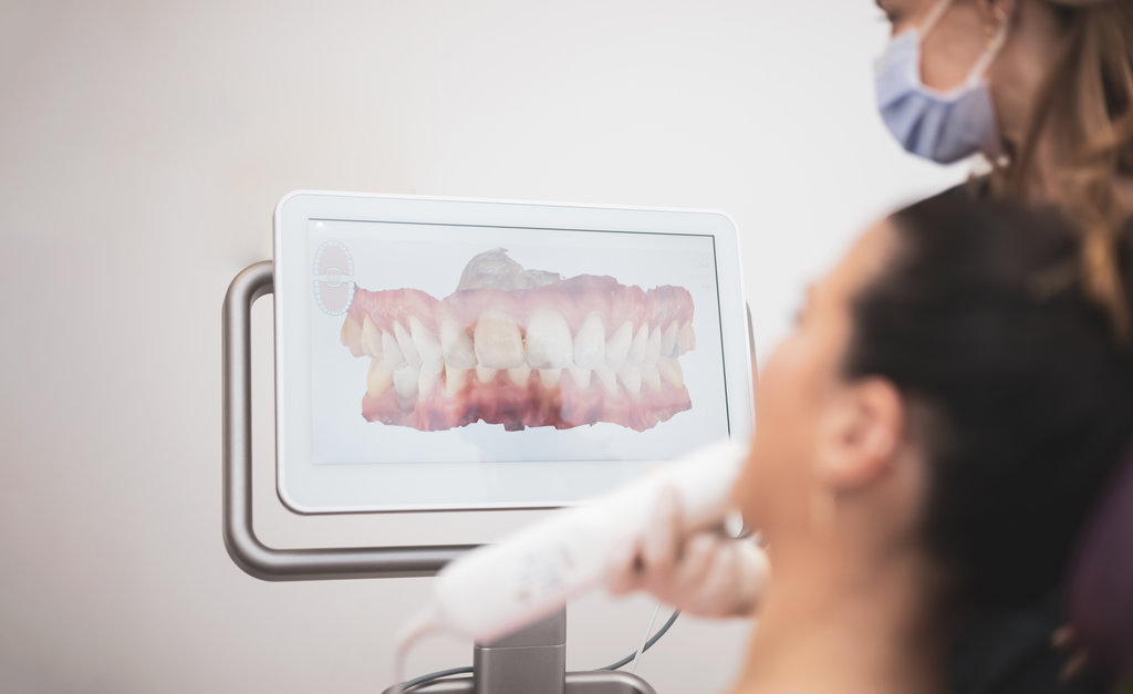 Woman dentist scanning patient's teeth with 3d dental scanner in modern clinic, 3d jaw scanner screen.