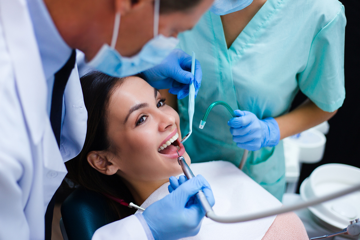 Her new dentist is not scary at all! Top view of dentist with his assistant examining his beautiful patient in dentist’s office